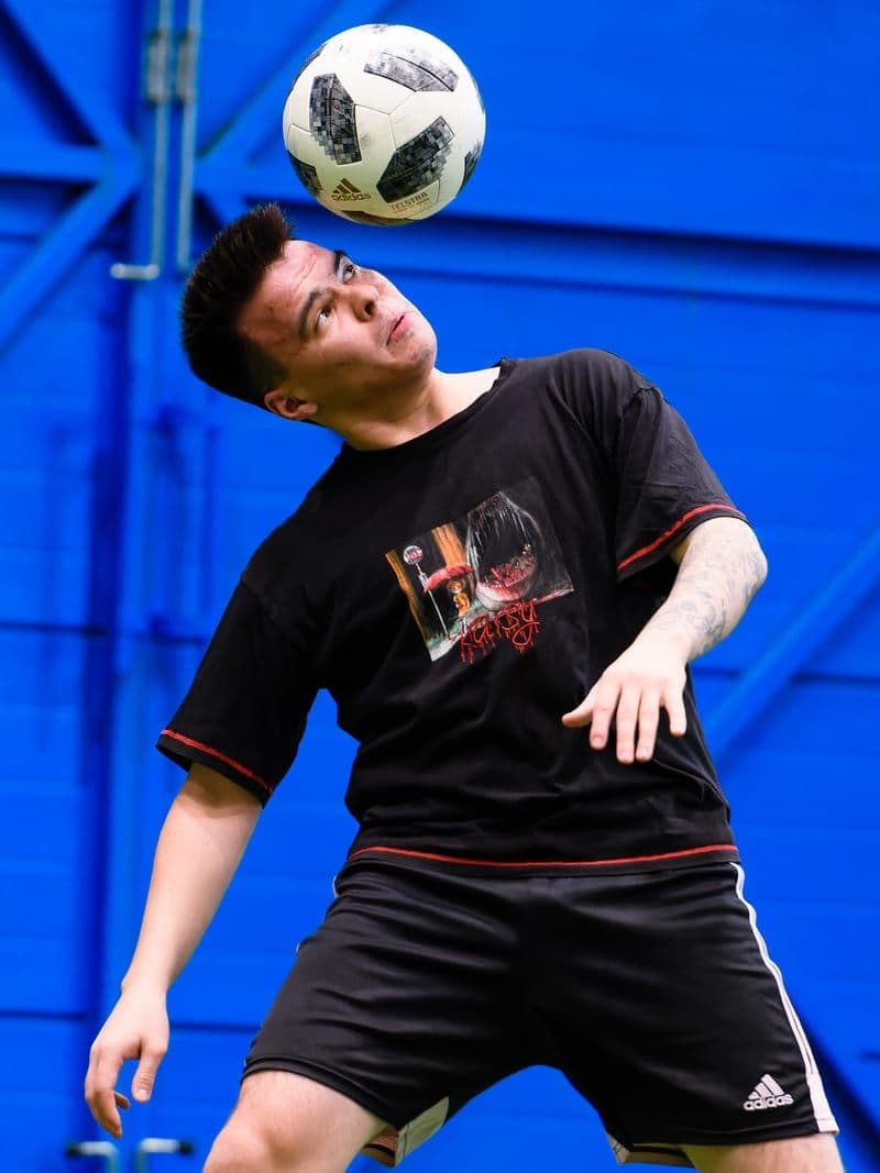 Игрок забивает головой на мини-футбольном поле